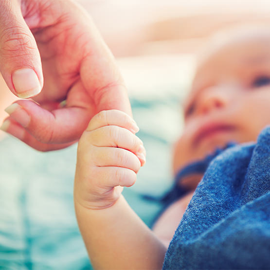 Photo of baby holding a parent's finger